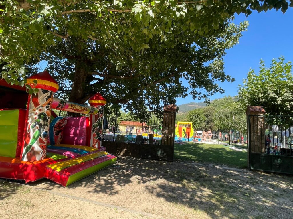 Castillo hinchable en la sombra junto a la piscina en Camping Rio Jerte