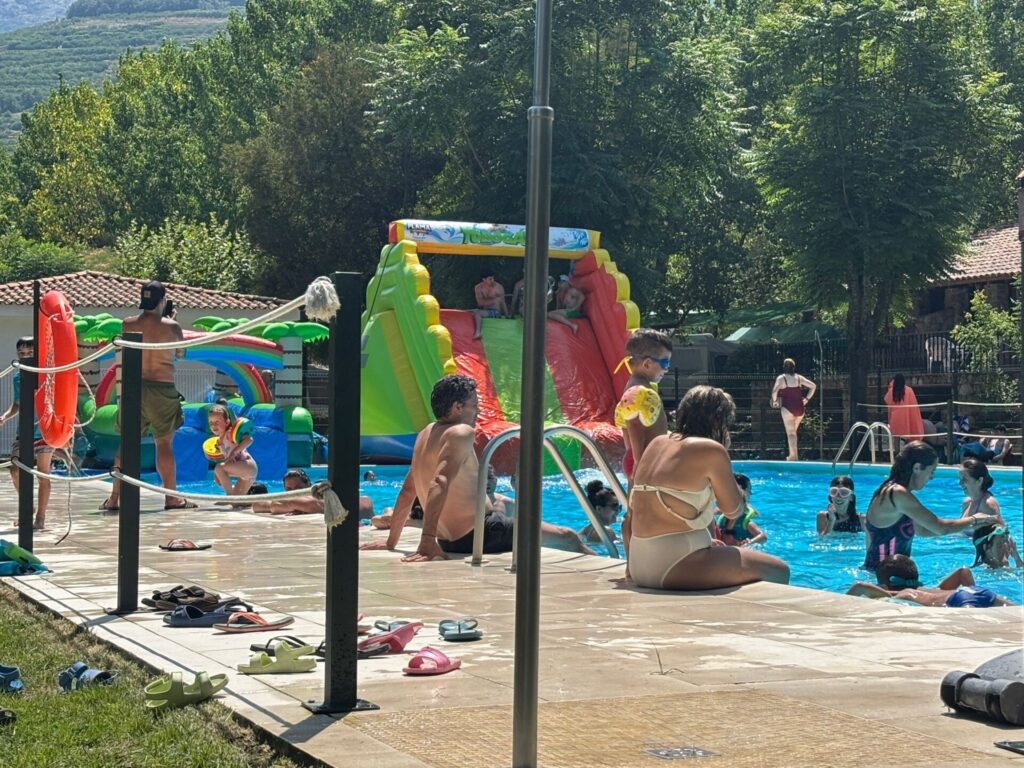 Piscina Camping Rio Jerte llena de gente con colchonetas y actividades actuáticas